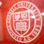 A color photo showing the Cornell University seal on a window.